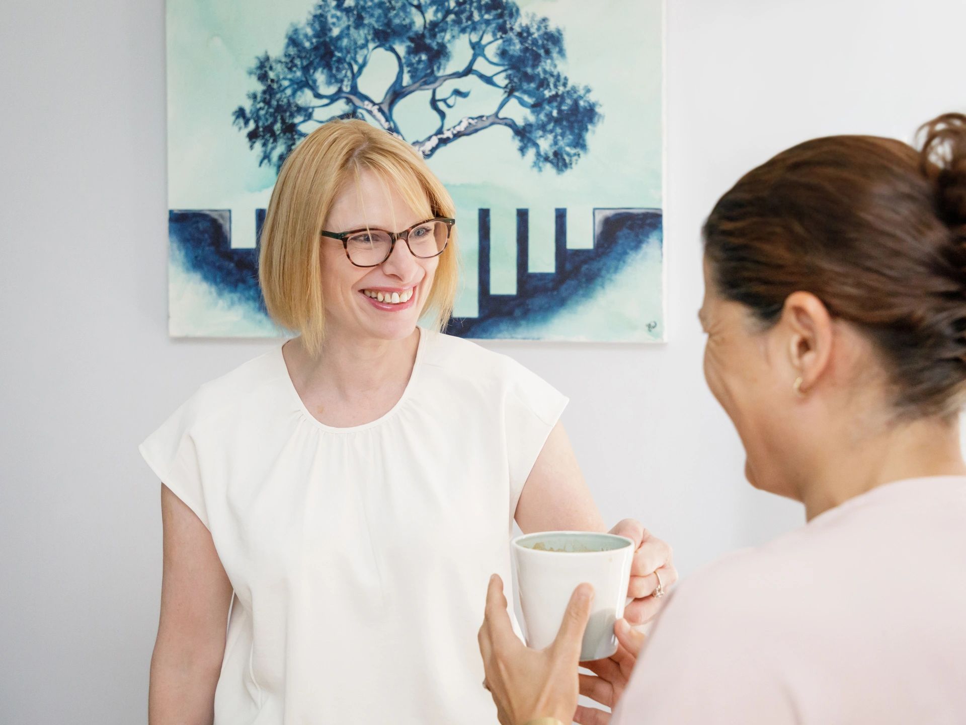 Accountant on phone call to client, in front of screen, with painting and poem behind her.