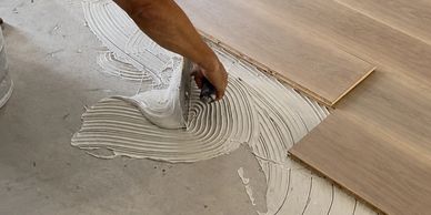 Applying adhesive for wooden floor tiles installation.
