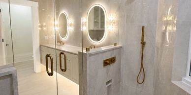 Modern bathroom with illuminated oval mirrors and glass shower enclosure.