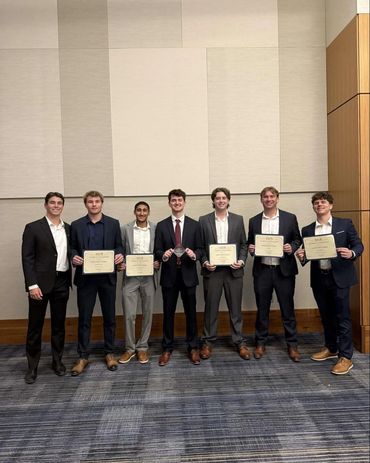 Seven young men in formal attire holding certificates and awards.