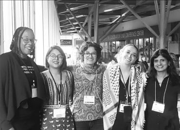 Group of five diverse women smiling indoors at a conference.