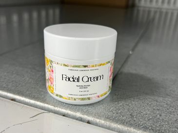 A jar of floral-labeled facial cream on a metallic surface.