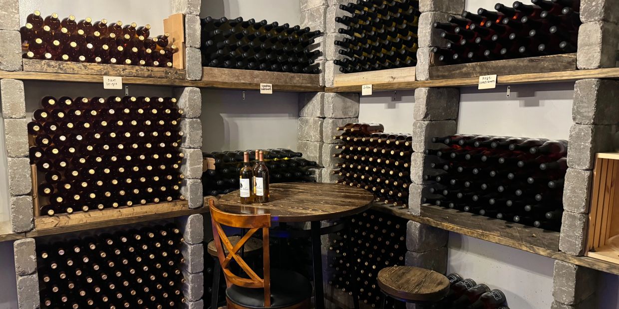Cozy wine cellar with wooden shelves and bottles arranged neatly around a small table.