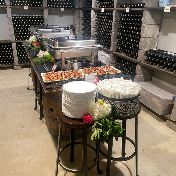 Buffet table set up in a wine cellar with plates and food.
