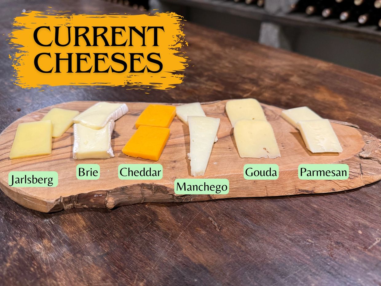 A wooden board displays six types of cheeses labeled from Jarlsberg to Parmesan.
