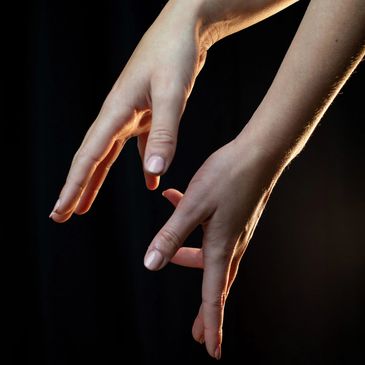 Two hands gracefully positioned against a dark background.