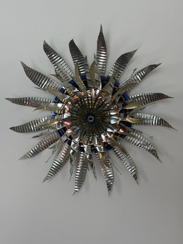 Metal sunburst wall decor with shiny, pointed blades.