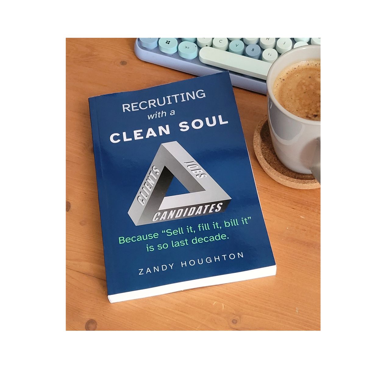 A book titled 'Recruiting with a Clean Soul' beside a cup of coffee on a wooden table.