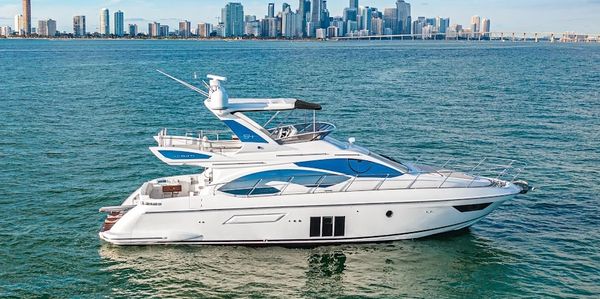 Luxury white yacht cruising near a city skyline on clear water.
