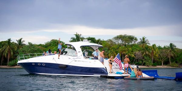 Group enjoying a boat party near a tropical island with an American flag.
