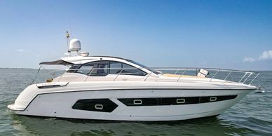 A sleek white luxury yacht floating on calm water under a clear sky.