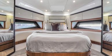 Modern bedroom with large bed and panoramic windows on a yacht.