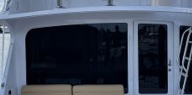 White boat exterior with a beige bench seat and glass door.