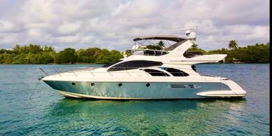Luxury yacht sailing on clear blue waters near a green shoreline.