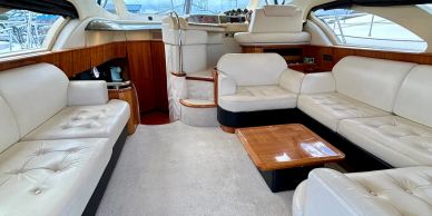 Luxurious yacht interior with cream leather sofas and wooden accents.