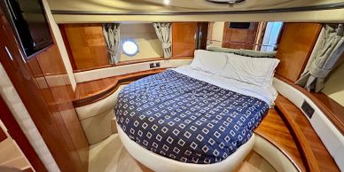 Cozy bedroom with curved bed and wooden interior on a boat.