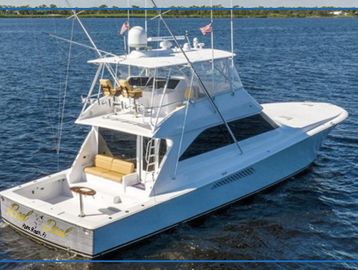 White fishing yacht on calm blue water with fishing rods.