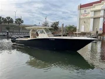 A sleek black motorboat docked in calm water near a marina.