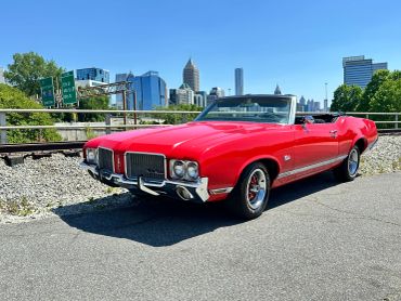 Classic red convertible car parked near train tracks.