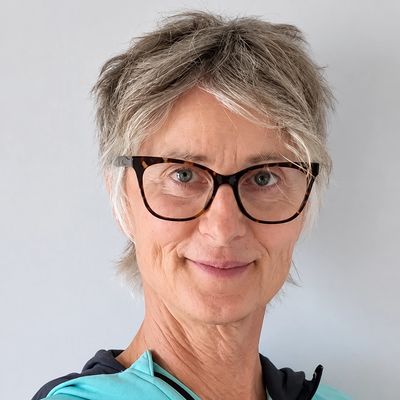 Older woman with short gray hair and glasses smiling.