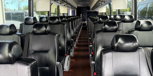 Interior of a modern bus with black leather seats arranged neatly.