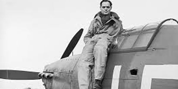 Pilot sitting on a vintage military aircraft's wing.