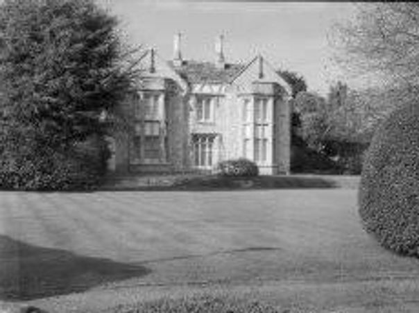 Historic mansion surrounded by well-maintained gardens and trees.