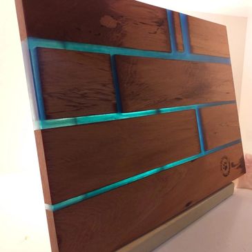 Wooden board with blue resin inlays creating a brick-like pattern.