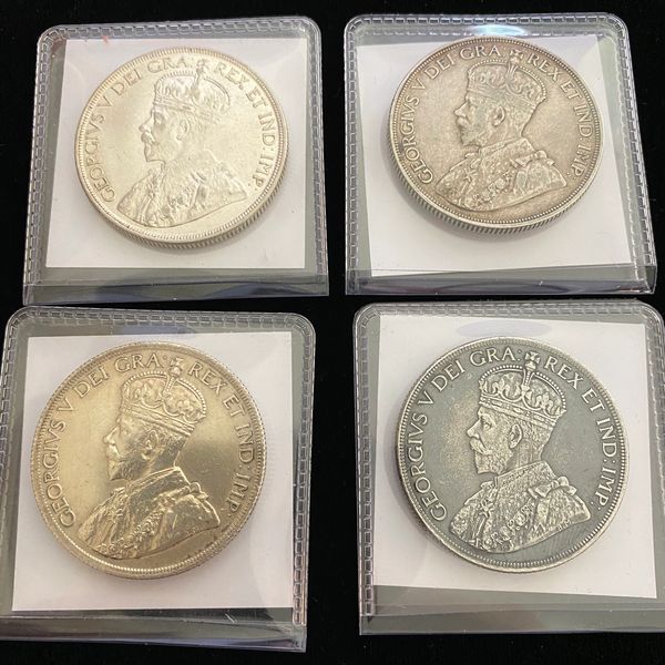 Four vintage coins featuring King George V in protective plastic holders.