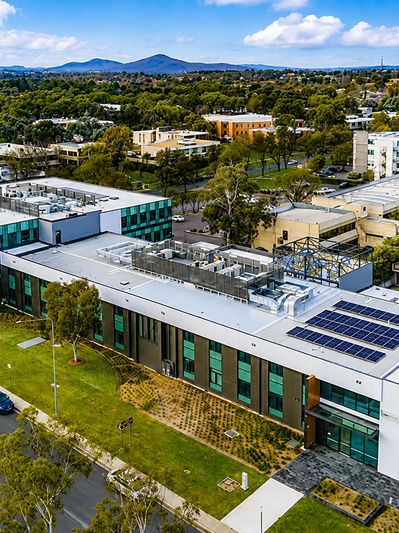 Aerial view of a modern building with solar panels and greenery.