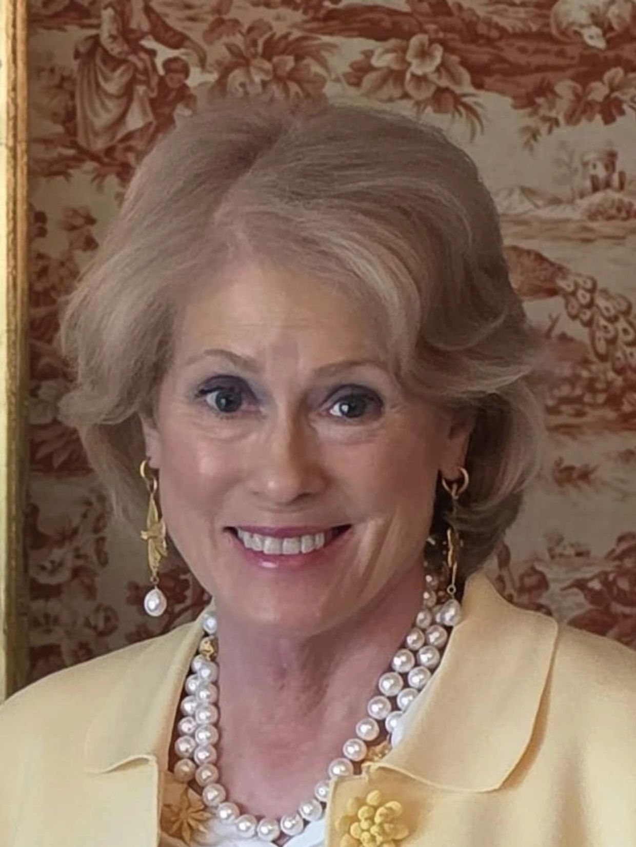 Smiling elderly woman with pearl necklace and earrings.