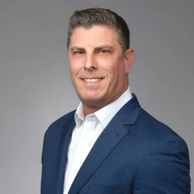 Professional man in a blue suit smiling at the camera.