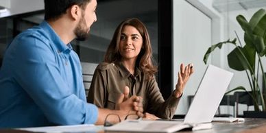 Two colleagues discussing work with a laptop in an office.