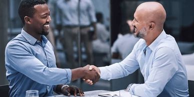 Two men shaking hands in a professional setting.