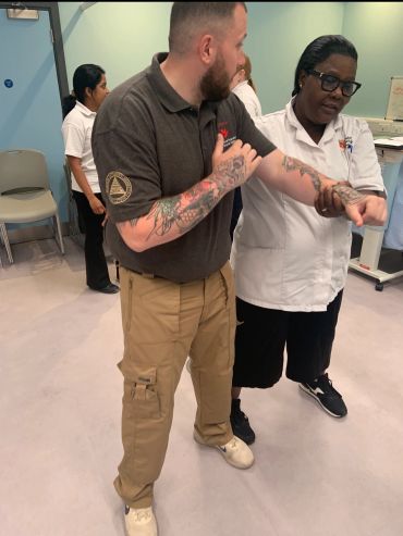 Man with tattoos getting medical help from a healthcare worker.