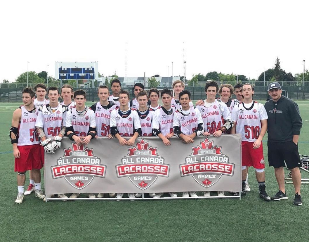 Youth lacrosse team posing with All Canada Lacrosse Games banner.