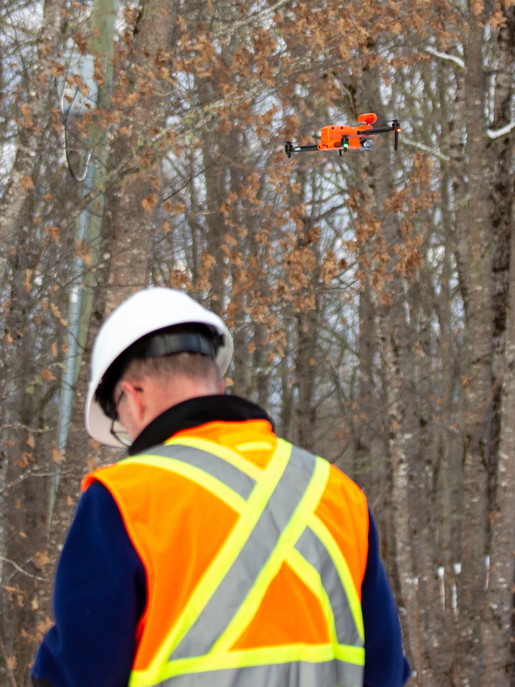 Pilot flying Autel EVO 2 640T dual near forest in winter.