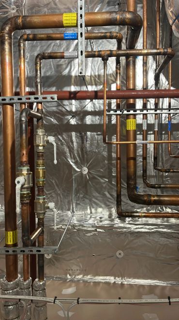 Intricate copper piping in a mechanical room with insulation.