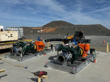Two industrial pumps on a concrete platform outdoors.