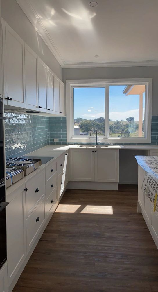 Bright modern kitchen with white cabinets and blue tile backsplash.