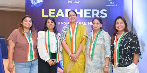 Group of five women wearing tricolor sashes at a leadership event.