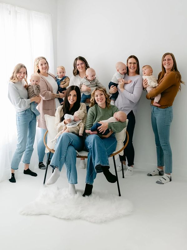 Group of women holding babies in a bright room.