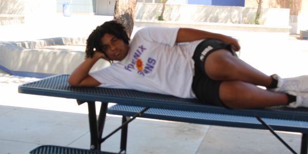Person lying on a blue picnic table outdoors.