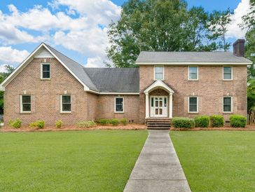 A large brick house with a front porch and a concrete walkway.