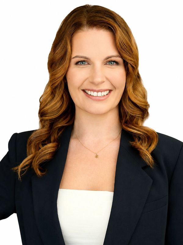 Smiling woman with wavy red hair in professional attire.