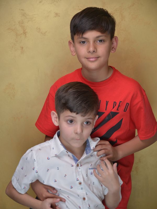 Two boys posing for a portrait against a plain background.