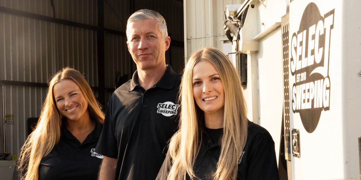 Three Select Sweeping employees pose smiling in branded black polo shirts.