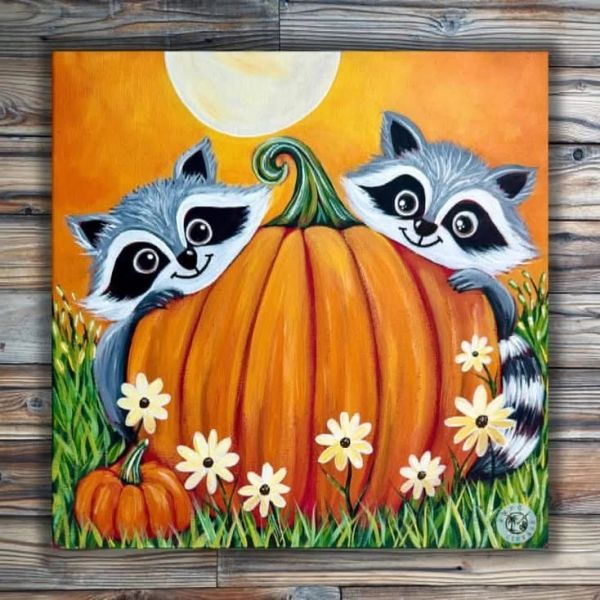 Two raccoons peeking from behind a large pumpkin.