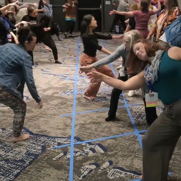 Group of people engaging in a lively dance or movement activity indoors.