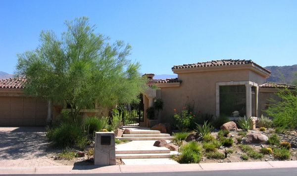 A southwestern-style house with desert landscaping and a clear blue sky.